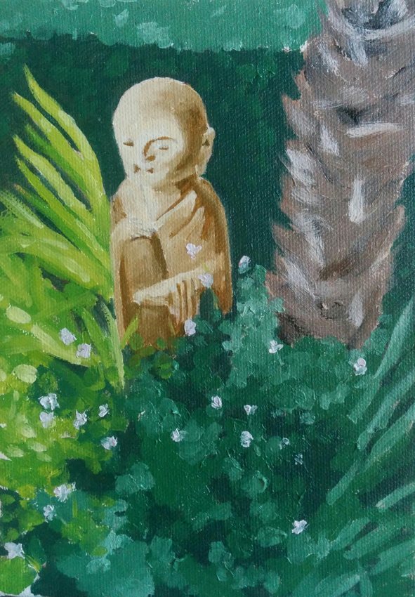 Little monk: a small monk figurine in sunlight among green leaves.