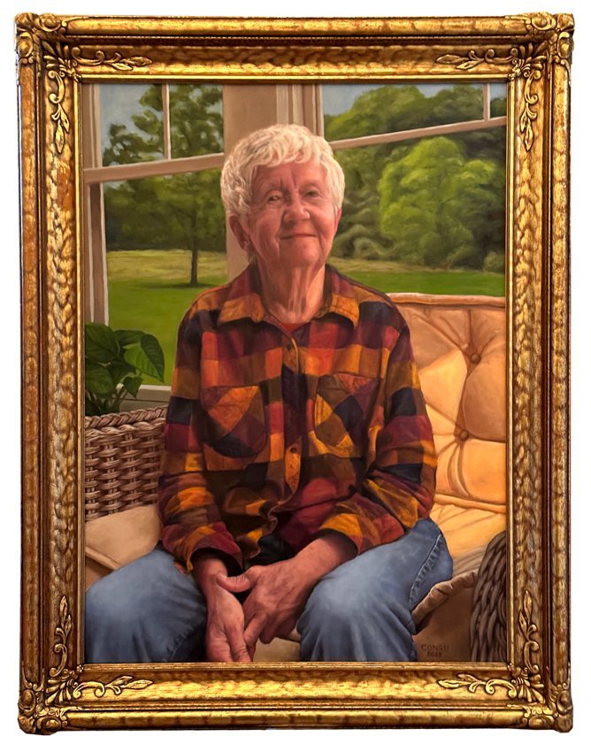 Finished oil portrait of Reva, an older woman with white hair in a plaid shirt, seated on a wicker couch with the family farm through the window, in a gold frame.